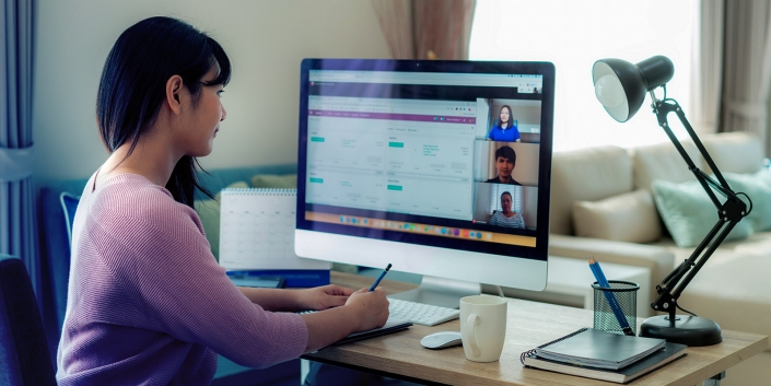 Back view of Asian business woman talking to her colleagues about plan in video conference. Multiethnic business team using computer for a online meeting in video call. Group of people smart working from home.